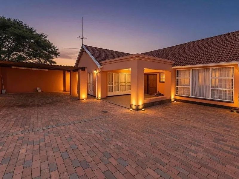 A well-maintained front exterior featuring a paved driveway, covered carport, and a welcoming entrance porch with integrated outdoor lighting.