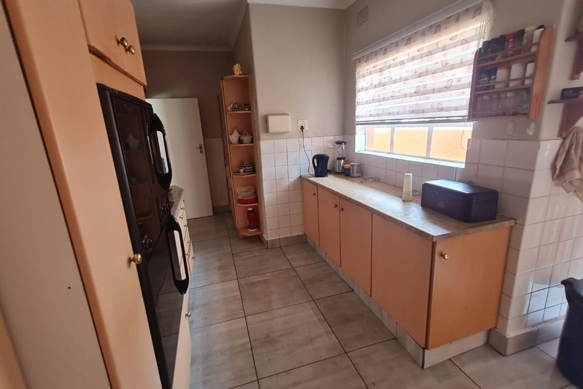 A functional kitchen featuring wooden cabinetry, tiled splashbacks, and tiled flooring, offering a practical layout with ample counter space.