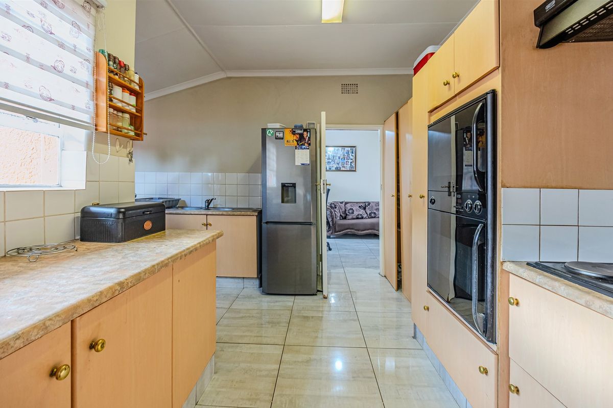 A functional kitchen featuring built-in cabinetry, integrated oven, extractor fan, and tiled flooring, offering a practical layout for daily meal preparation.