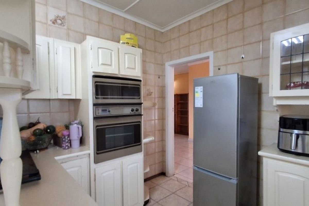 A dated kitchen featuring built-in wall ovens, tiled walls, and traditional cabinetry, offering a functional layout with potential for modern renovation.