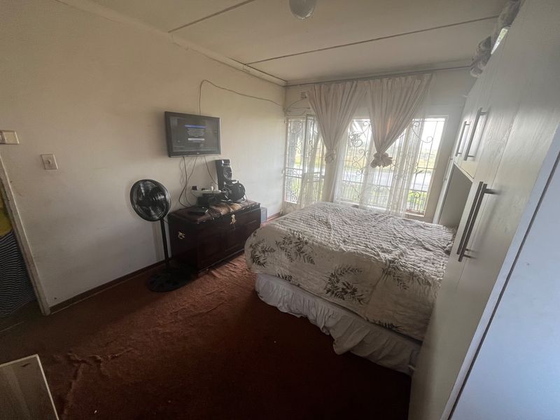 A bedroom featuring built-in cabinetry, carpeted flooring, and security bars on the windows.