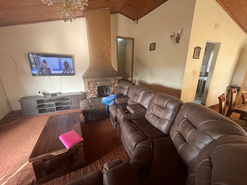 Spacious living room featuring a vaulted timber ceiling, a central fireplace, and direct access to adjacent living areas.