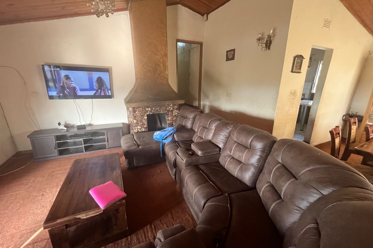 Spacious living room featuring a vaulted timber ceiling, a central fireplace, and direct access to adjacent living areas.