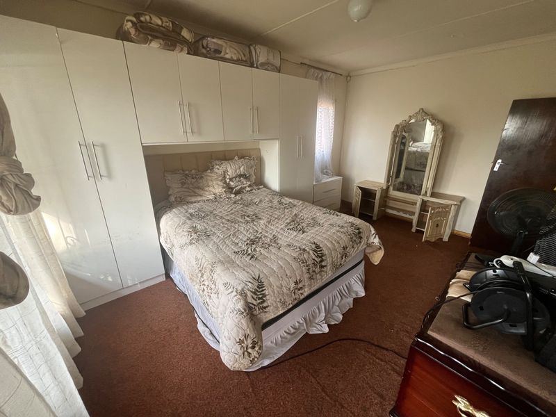 A bedroom featuring built-in white cabinetry surrounding the bed area, providing ample storage space with neutral wall finishes.