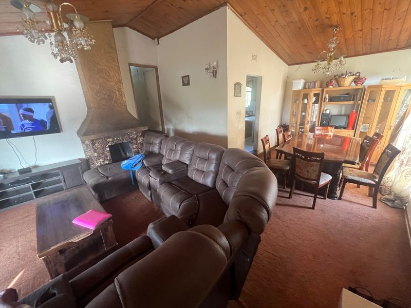 Open-plan living and dining area featuring a central fireplace, timber-clad vaulted ceilings, and carpeted flooring throughout.