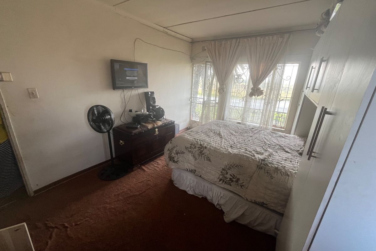 A bedroom featuring built-in cabinetry, carpeted flooring, and security bars on the windows.