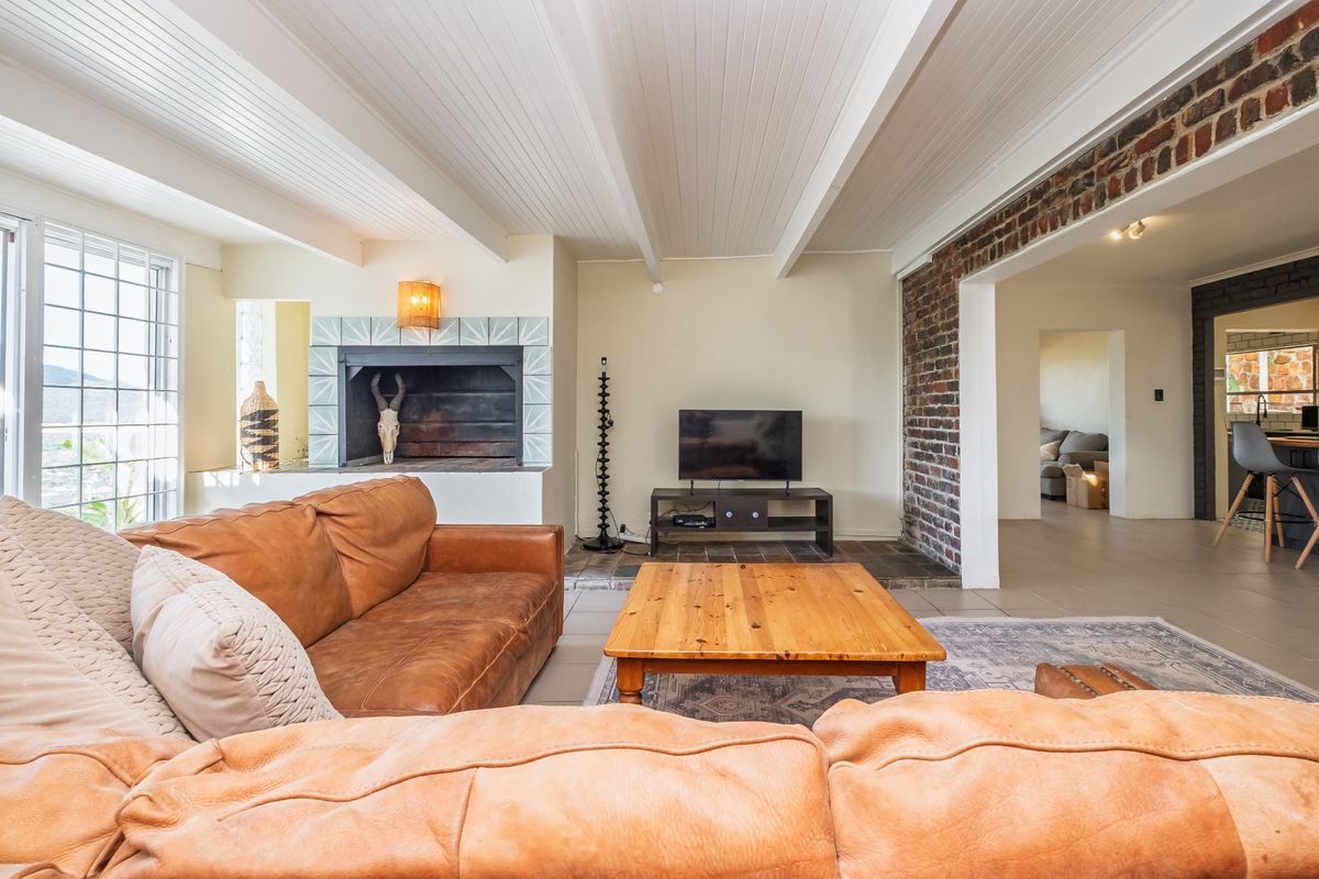 Spacious living room featuring a built-in fireplace, exposed brick accents, and white timber-paneled ceilings, creating a warm and inviting atmosphere.