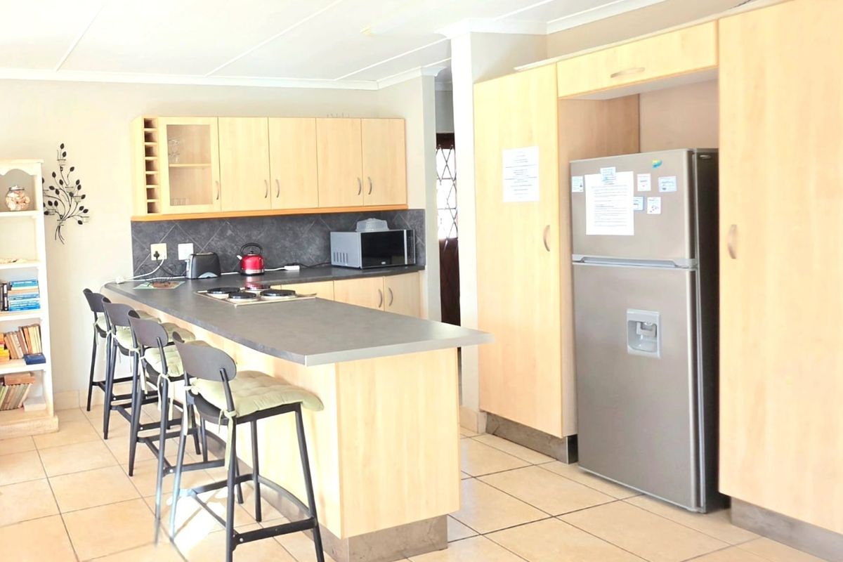 A functional kitchen featuring light wood cabinetry, a breakfast bar with integrated hob, tiled flooring, and ample storage space.