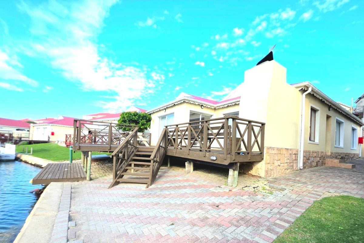 Waterfront property featuring a raised timber deck, paved patio area, and direct access to the canal.