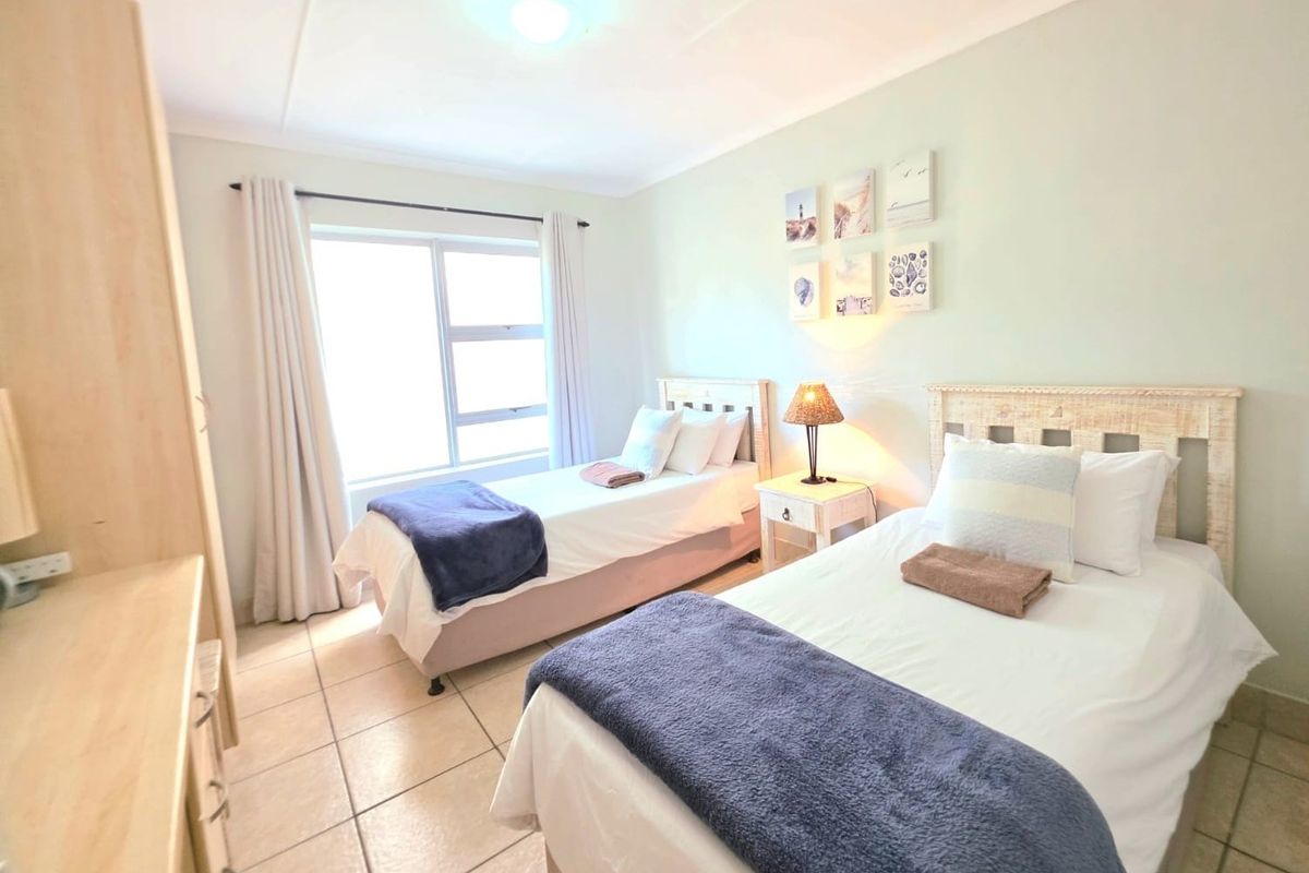 A bright bedroom featuring tiled flooring, a large window with curtains, and built-in cabinetry.