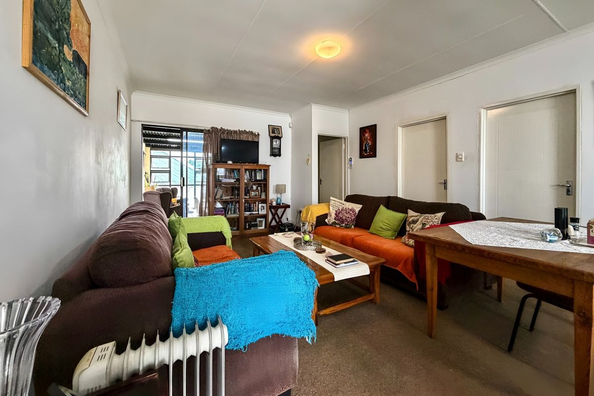 A living room area featuring carpeted flooring, a flush mount ceiling light, and a sliding glass door providing access to an outdoor space.