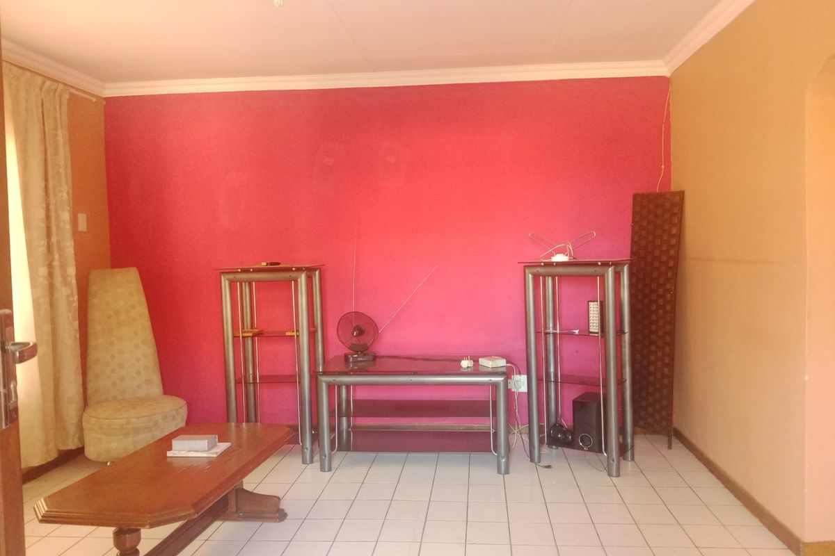 A living room featuring tiled flooring and coved ceilings, currently finished with a bold pink accent wall.