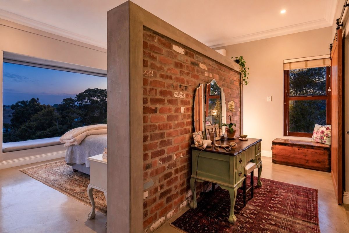 Spacious bedroom featuring an exposed brick partition wall, polished concrete floors, and a large picture window with scenic views.