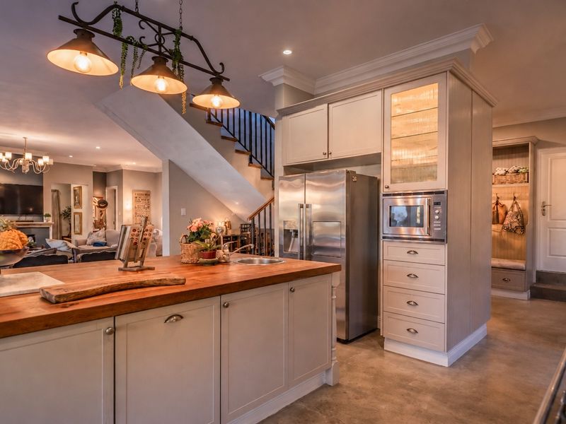 Spacious open-plan kitchen featuring a large island with a wooden countertop, custom cabinetry, built-in appliances, and seamless flow into the living area.