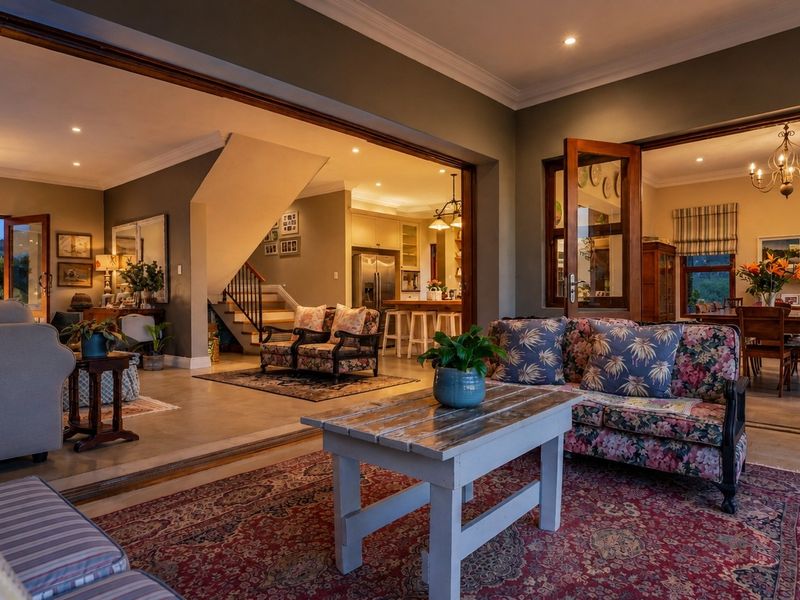 Spacious open-plan living area featuring tiled floors, recessed lighting, and seamless flow between the lounge, dining room, and kitchen with timber-framed glass doors.