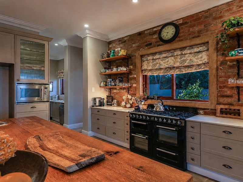 A well-appointed kitchen featuring exposed brick walls, a large timber island bench, and a professional-style gas range cooker with integrated cabinetry.