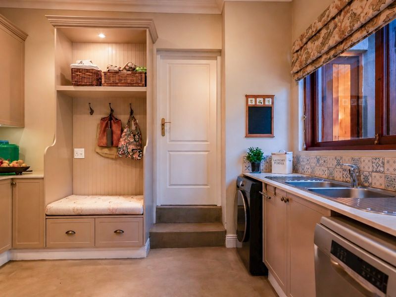 A functional laundry room featuring built-in cabinetry, a stainless steel sink, tiled backsplash, and a convenient built-in bench seating area.