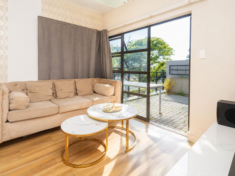 Living room featuring wood-look flooring and large sliding glass doors providing direct access to an outdoor patio area.