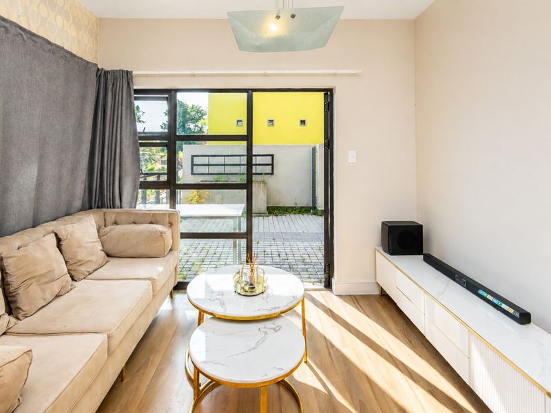 A bright living room featuring wood-look flooring and large glass sliding doors that provide direct access to an outdoor patio area.