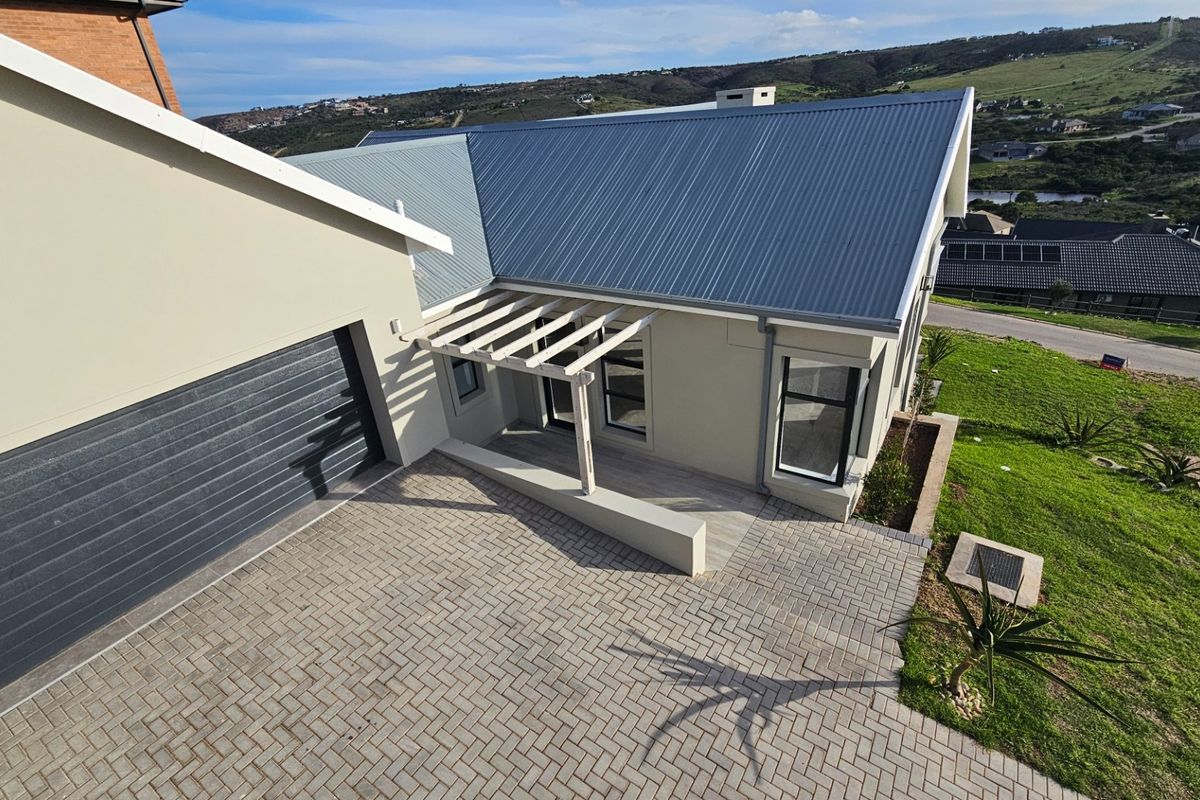 Aerial view of the property entrance featuring a paved driveway, single garage, and a covered pergola entryway with modern architectural finishes.