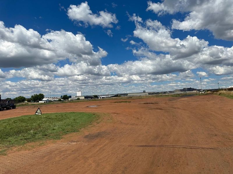 Expansive undeveloped industrial land plot with unpaved ground, offering significant space for potential development or storage.