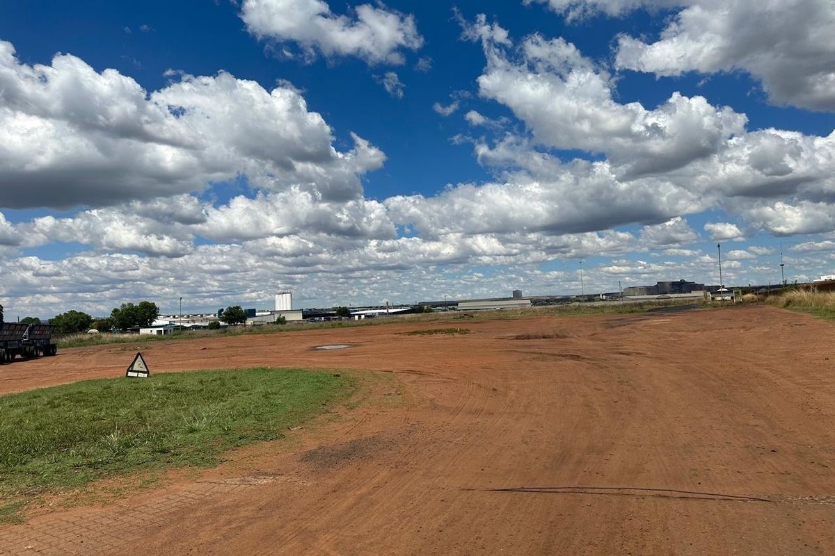 Expansive undeveloped industrial land plot with unpaved ground, offering significant space for potential development or storage.
