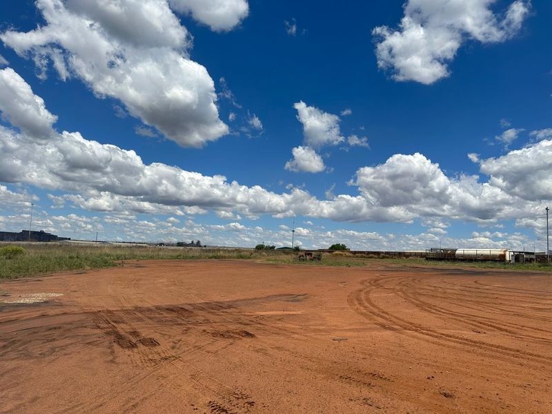 Expansive industrial land parcel featuring an unpaved, open yard area suitable for heavy vehicle access or storage.