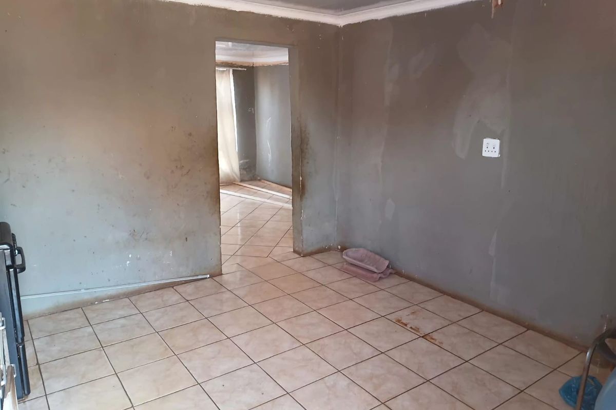 An empty living area featuring ceramic floor tiles and unfinished plastered walls, presenting a blank canvas for renovation and interior design updates.