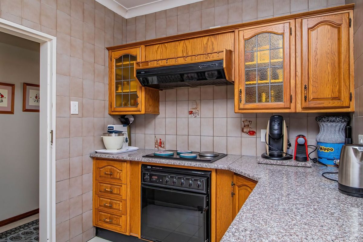 A functional kitchen featuring traditional wooden cabinetry, a built-in oven with hob, extractor fan, and durable tiled splashbacks.