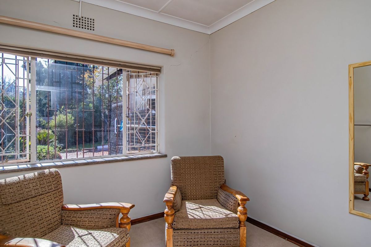 A bedroom featuring security bars on the window and a neutral wall finish, providing a functional space with natural light.