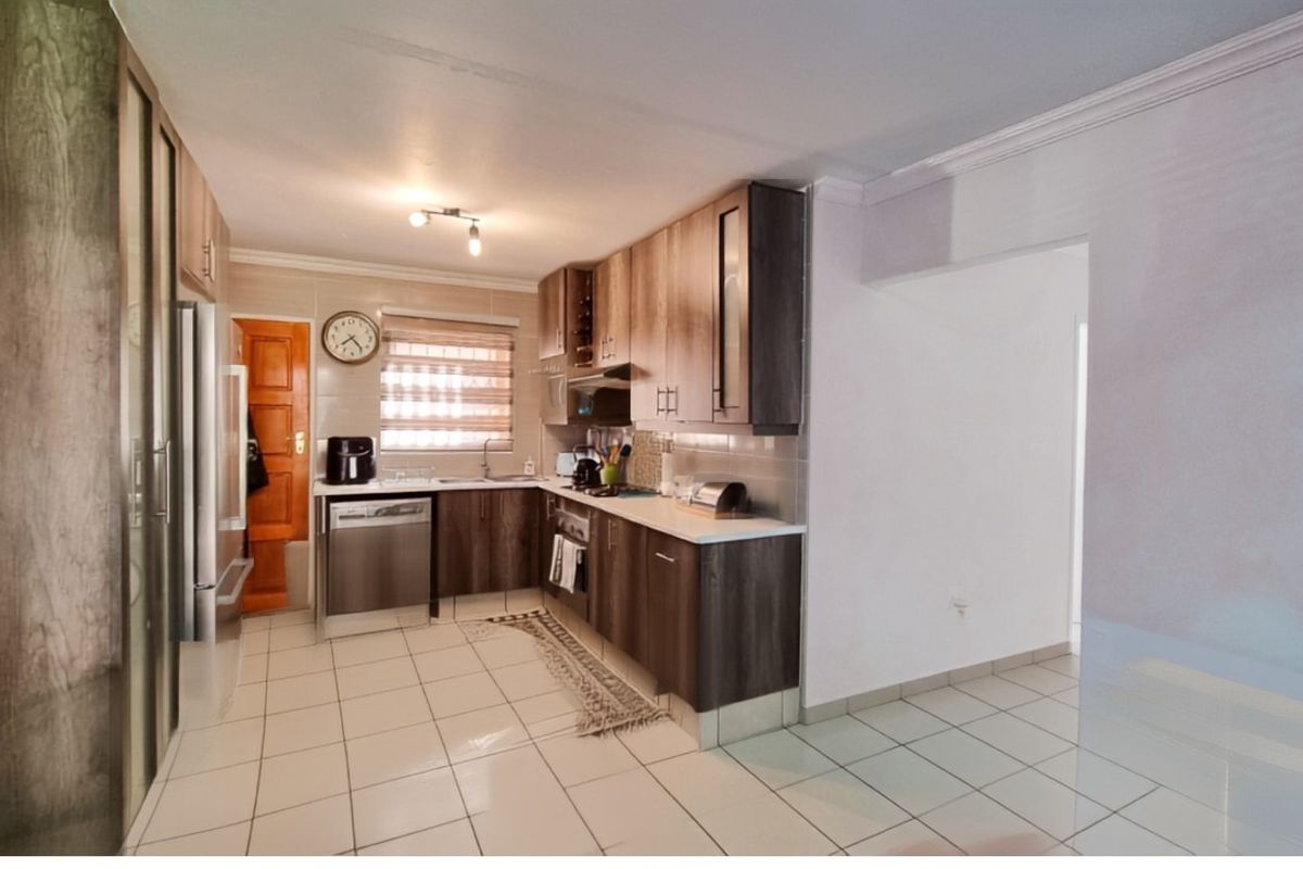 A functional kitchen featuring wood-look cabinetry, tiled flooring, and integrated appliance space, offering a practical layout for daily meal preparation.