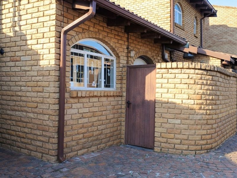 Exterior view of an apartment entrance featuring face-brick facade, arched window, and paved driveway area.