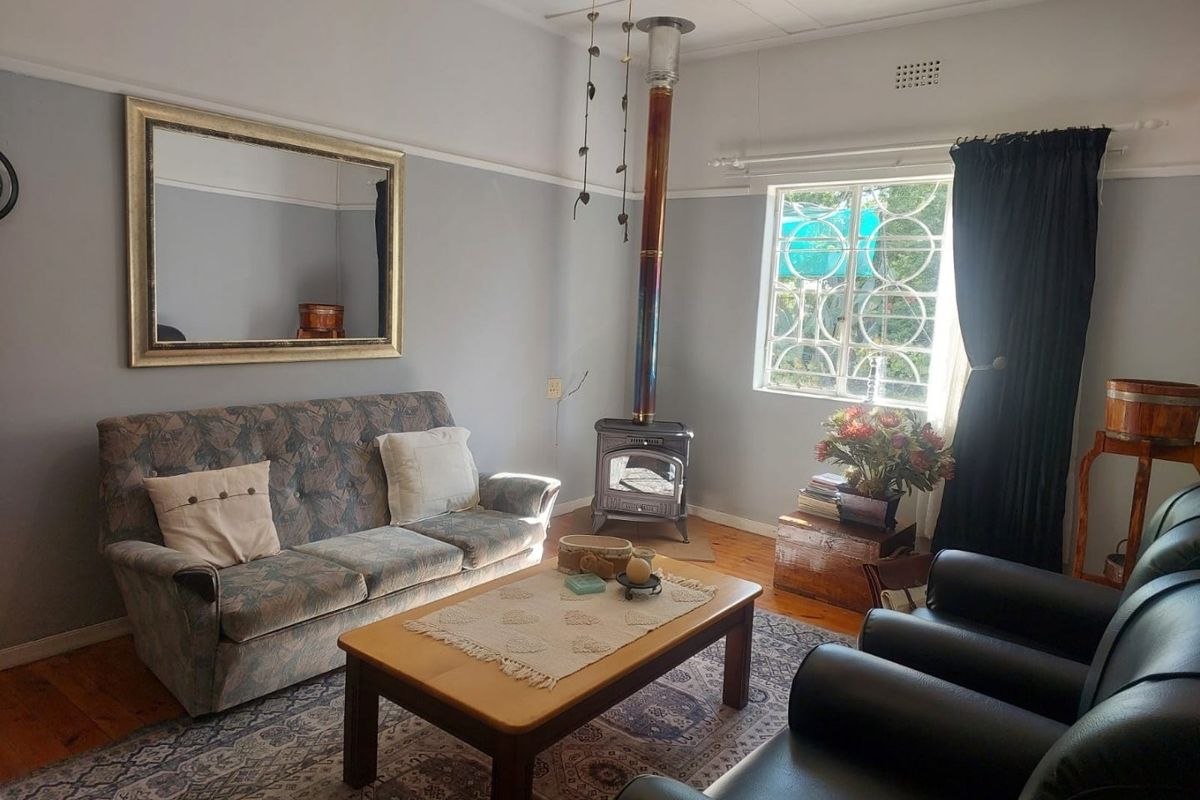 A cozy living room featuring a cast-iron wood-burning fireplace, original timber flooring, and decorative picture rails.
