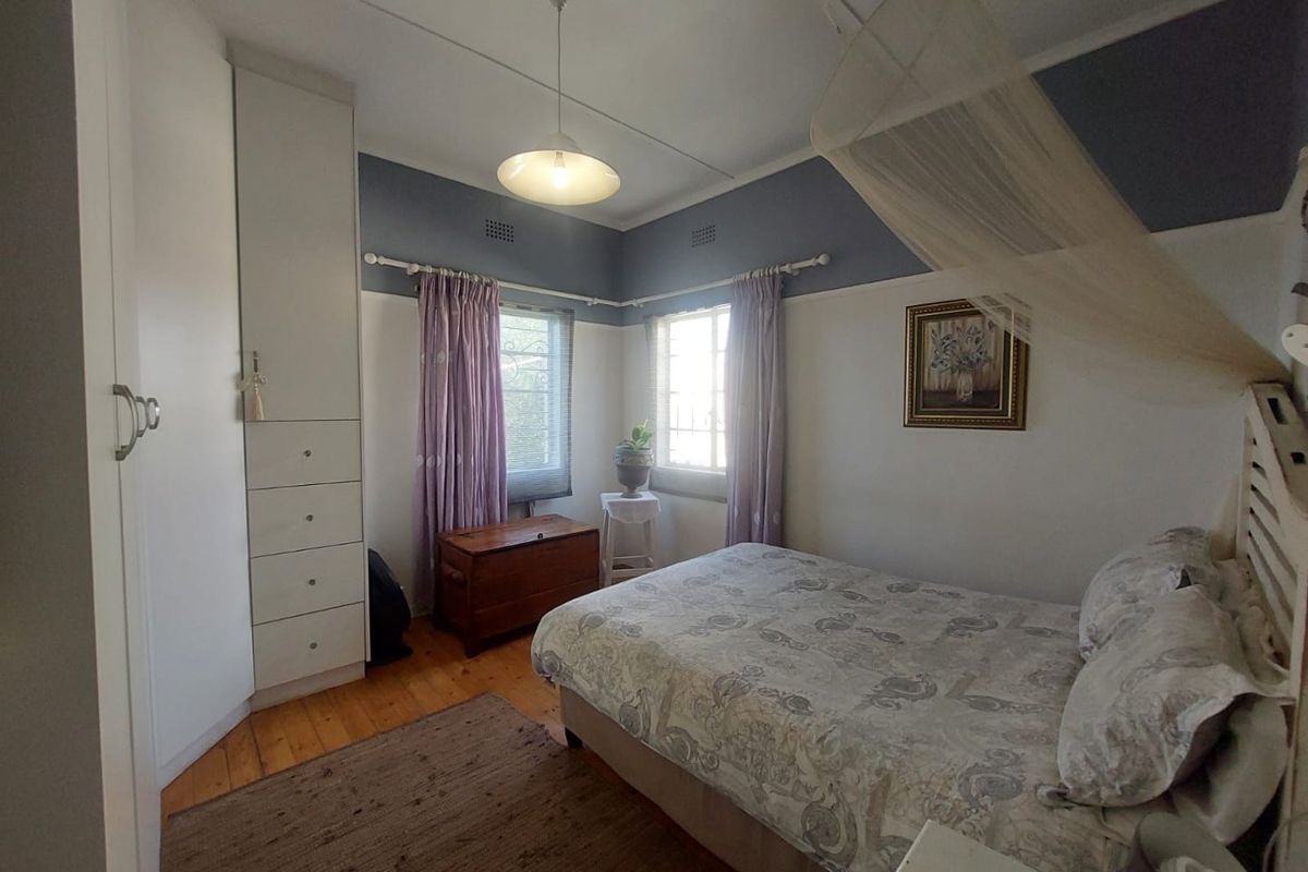 A cozy bedroom featuring original timber flooring, built-in cabinetry, and large windows that provide natural light.