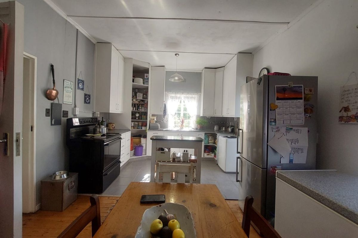A functional kitchen featuring white cabinetry, a freestanding stove, and tiled flooring, providing a practical workspace with integrated storage solutions.