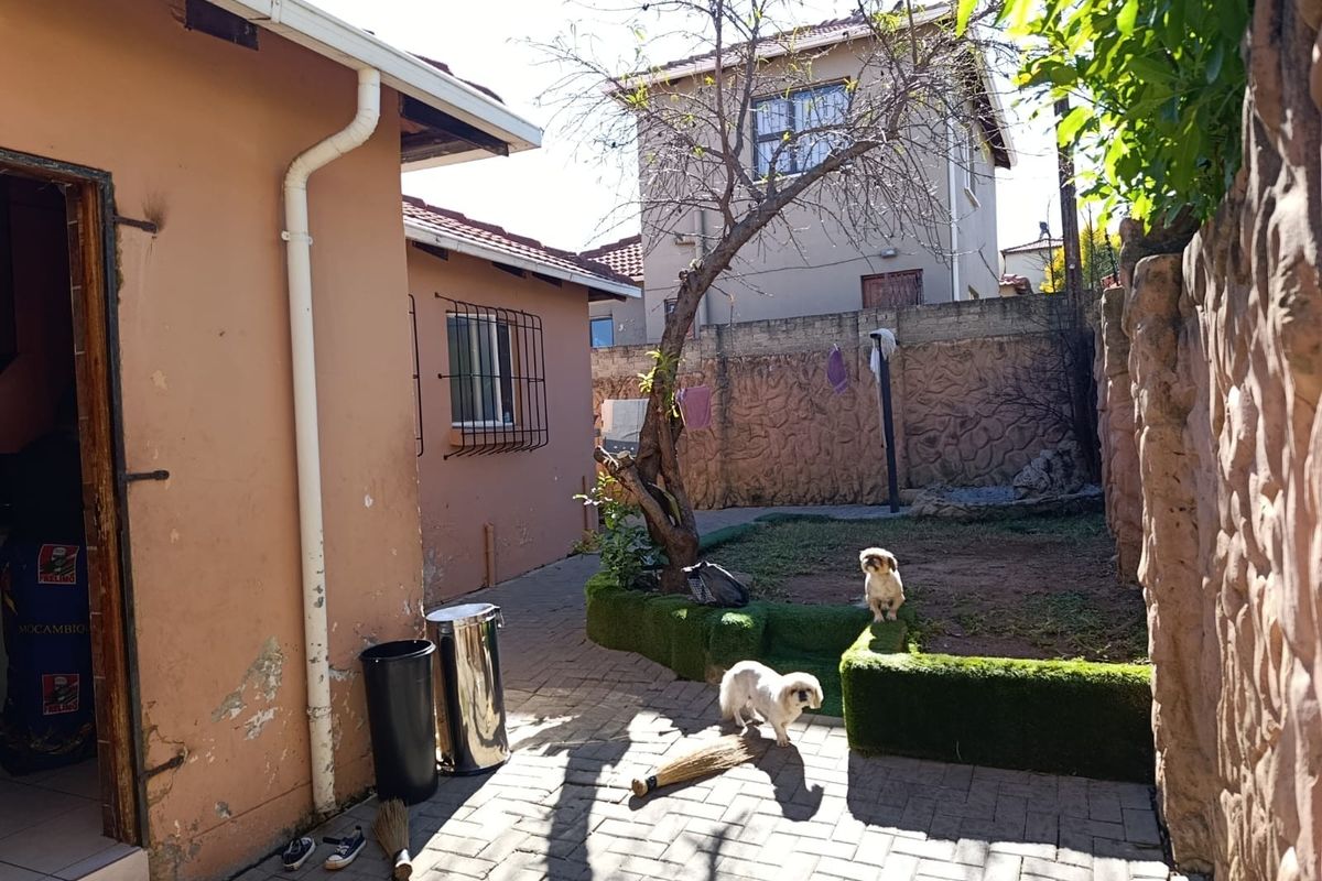 A rear courtyard area featuring paved flooring, a small garden bed with artificial turf, and perimeter boundary walls.