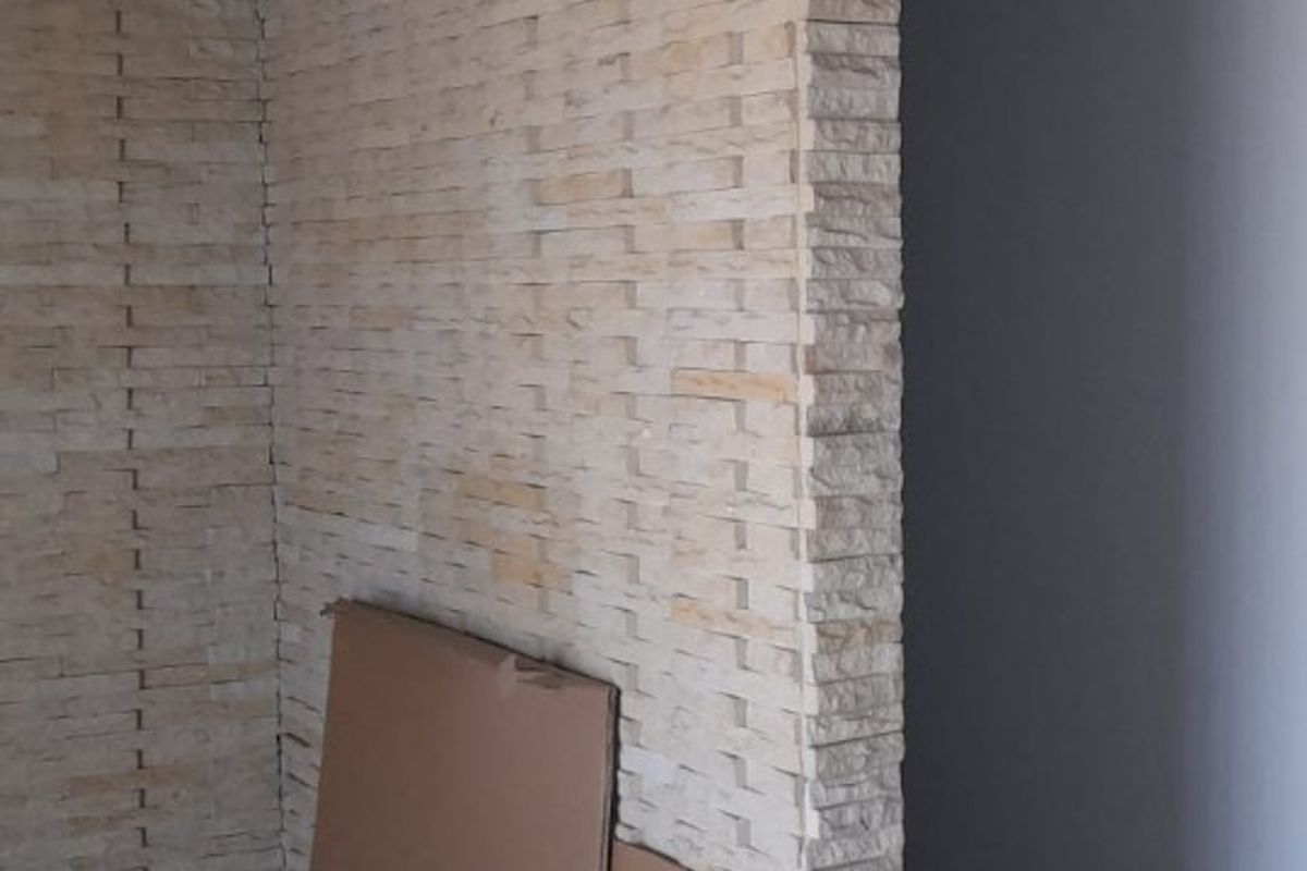 Interior space featuring a decorative stone-clad partition wall, crown molding, and tiled flooring.