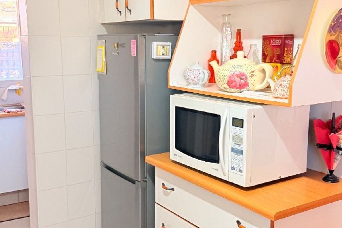 A functional kitchen area featuring built-in cabinetry, tiled flooring, and a dedicated storage unit with open shelving.