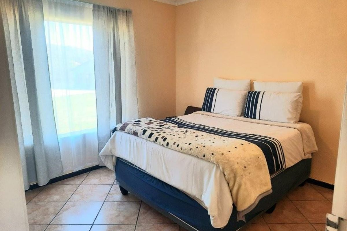A bedroom featuring tiled flooring and a large window with natural light, providing a functional and comfortable living space.