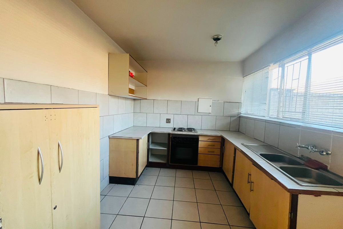 A functional kitchen featuring built-in cabinetry, a stove, oven, and double sink with tiled splashbacks and flooring.