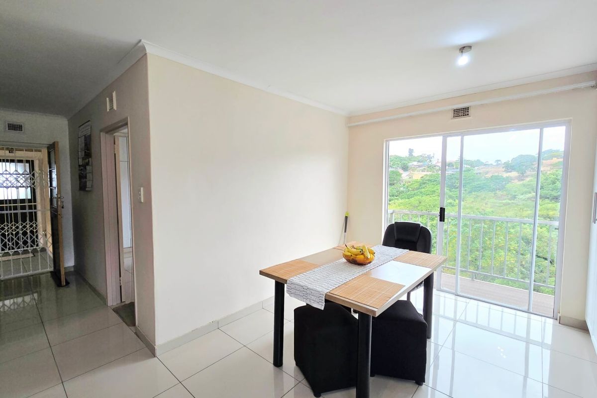 Bright living area featuring large sliding glass doors leading to a balcony, neutral tiled flooring, and clean finishes throughout.