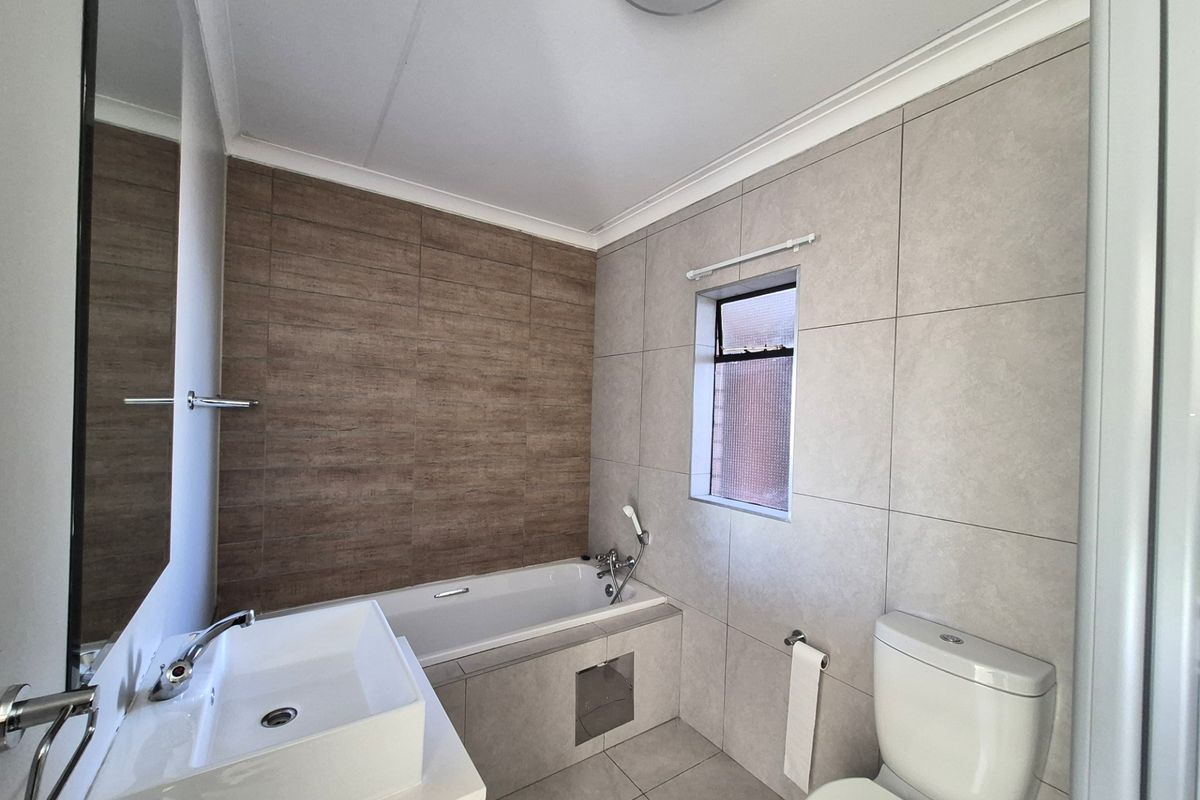 Modern bathroom featuring a built-in bathtub, contemporary vessel sink, and neutral floor-to-ceiling tiling.