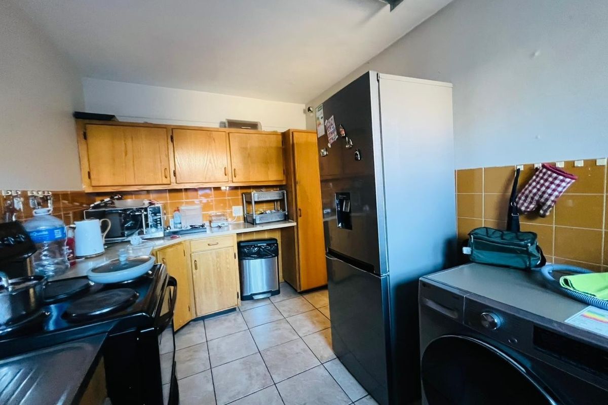 A functional kitchen featuring wooden cabinetry, tiled splashbacks, and tiled flooring, providing a practical layout for daily meal preparation.