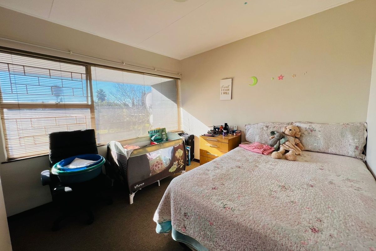 A bedroom featuring large windows with fitted horizontal blinds and neutral wall finishes.