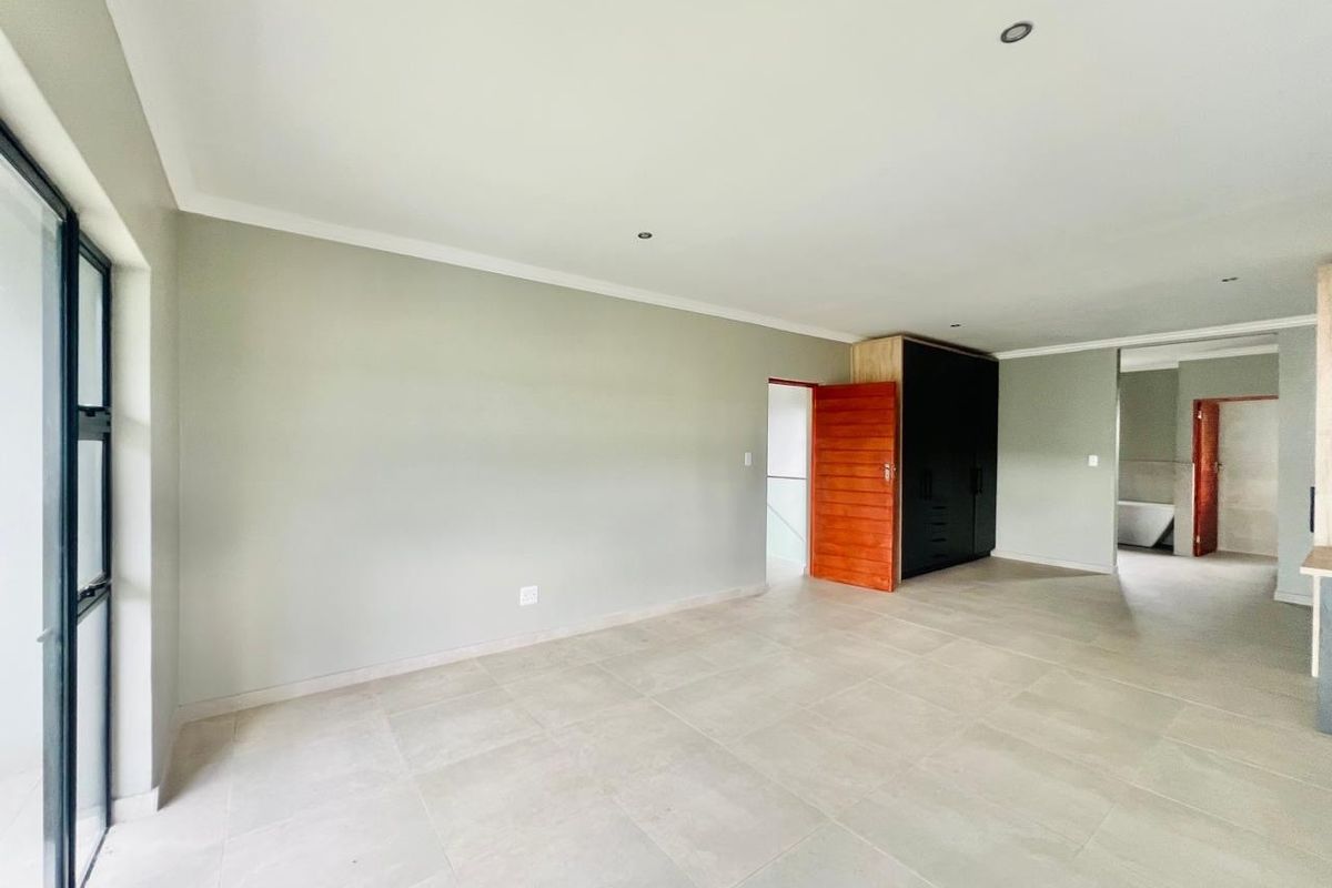 Spacious bedroom featuring neutral tiled flooring, built-in cabinetry, recessed ceiling lighting, and direct access to an adjoining bathroom.