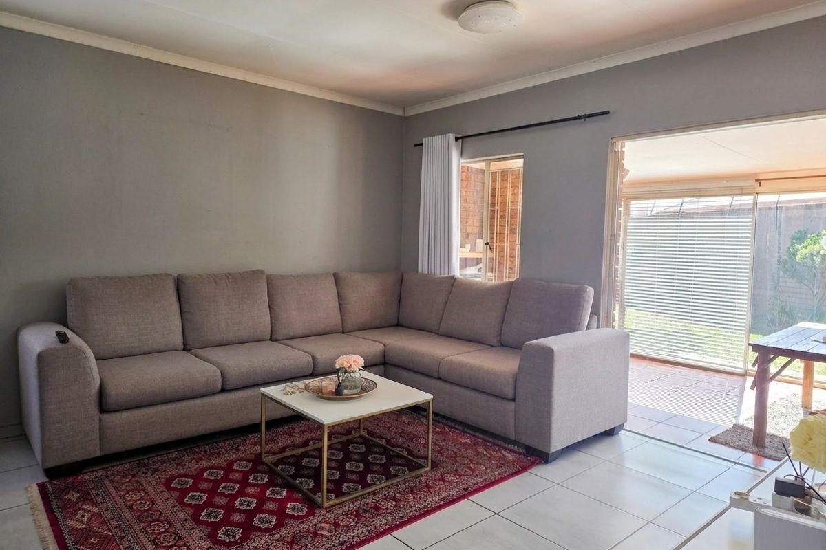 A comfortable living room featuring neutral wall tones, tiled flooring, and direct access to an outdoor patio area through sliding glass doors.