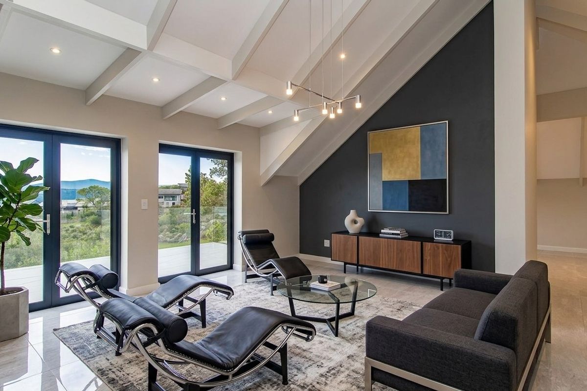Spacious living room featuring vaulted ceilings with exposed beams, large glass doors leading to an outdoor area, and a modern dark feature wall.