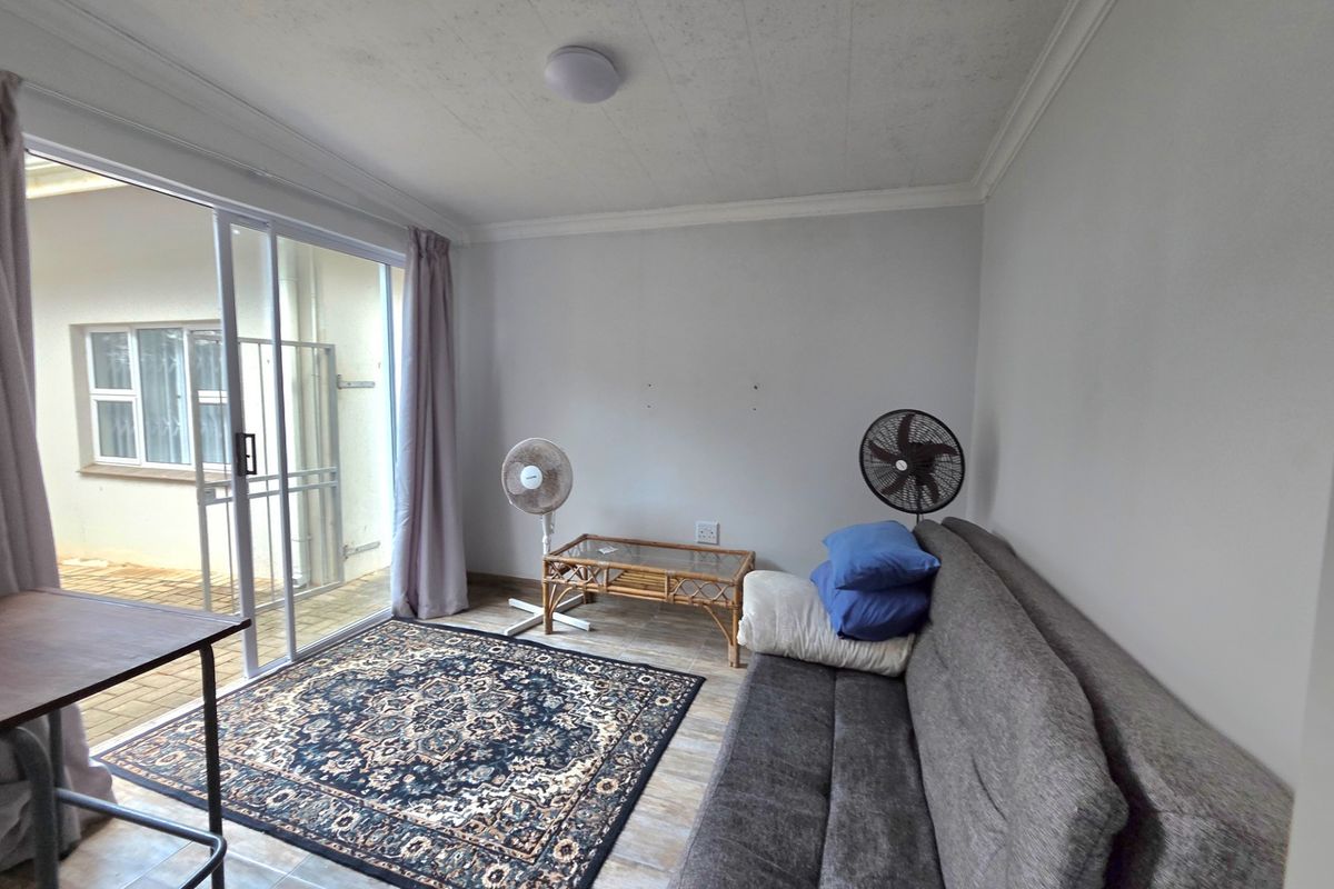 A living room featuring tiled flooring and a large sliding glass door providing access to an outdoor area.