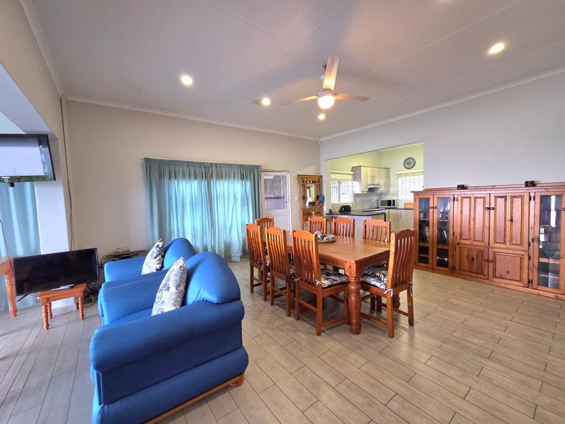 Spacious open-plan living and dining area featuring tiled flooring, recessed lighting, a ceiling fan, and an adjoining kitchen with built-in cabinetry.