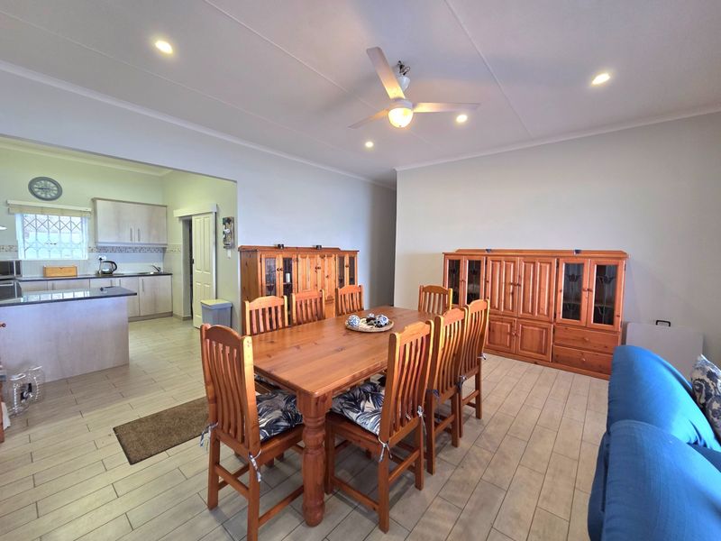 Open plan living and dining area featuring tiled flooring, recessed lighting, and a functional kitchen with built-in cabinetry and island.